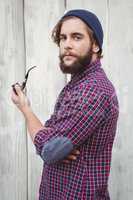 Side view of hipster holding smoking pipe