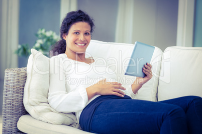 Portrait of happy woman reclining on sofa with tablet