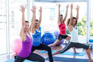 Cheerful women doing low warrior pose in fitness studio