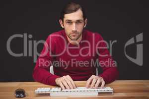 Portrait of serious man typing on keyboard at desk