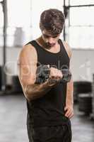 Focused handsome man lifting dumbbell