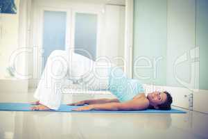 Happy pregnant woman lying on floor in bridge pose