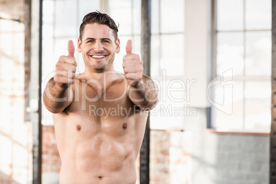 Muscular man standing in front of the camera with his thumbs up