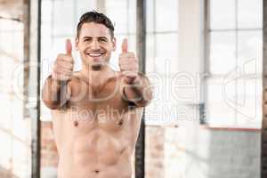 Muscular man standing in front of the camera with his thumbs up