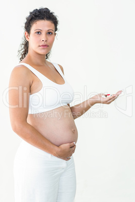 Serious pregnant woman holding pills