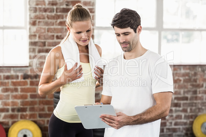 Woman discussing her performance on clipboard with trainer