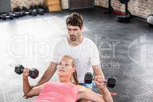 Fit woman lifting dumbbells with trainer