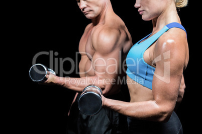 Midsection side view of man and woman lifting dumbbells