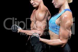 Midsection side view of man and woman lifting dumbbells