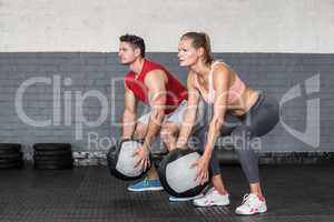 Muscular couple doing ball exercise