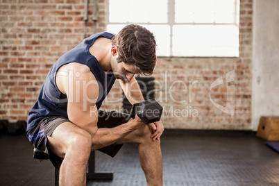 Man lifting dumbbell while sitting