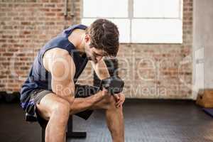 Man lifting dumbbell while sitting