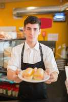 Confident male worker with sandwich  in bakery