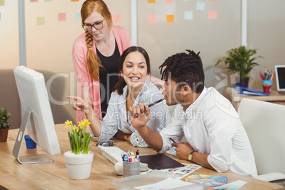 Businesswoman showing something to colleagues on computer during