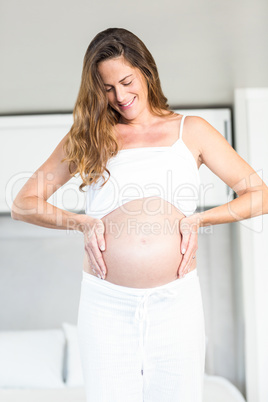 Happy woman looking at pregnant belly