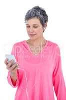 Mature woman using mobile phone while listening music