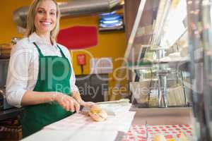 Female worker cutting sandwich on counter