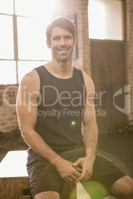 Portrait of a smiling man sitting on plyo box