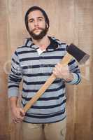 Portrait of confident hipster with hooded shirt holding axe