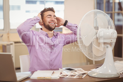 Relax businessman sitting by electric fan