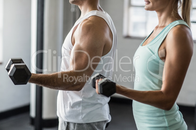 couple exercising with dumbbells in gym