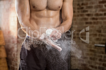 Midsection of muscular man applying chalk powder