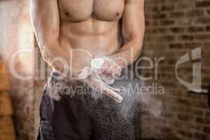 Midsection of muscular man applying chalk powder