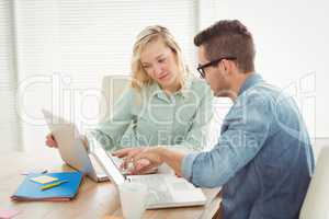 Man and woman discussing while using laptop