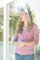 Happy woman standing by glass window