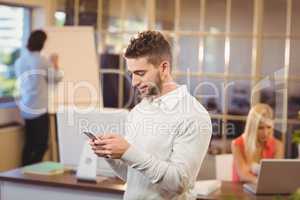 Businessman texting on phone with colleagues working in office