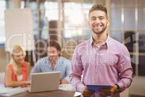 Businessman using digital tablet in office with colleagues on la