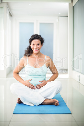 Portrait of smiling pregnant woman touching her belly