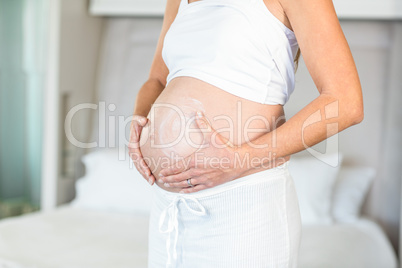 Midsection of woman with moisturizer on belly