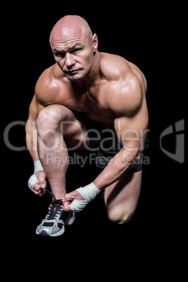 Portrait of muscular man tying laces