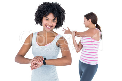 Woman wearing wristwatch while female friend exercising