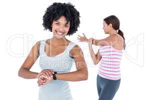 Woman wearing wristwatch while female friend exercising