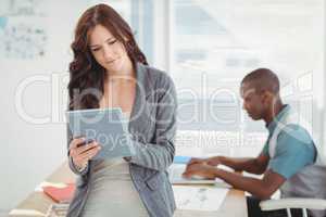 Woman using digital tablet with man working at desk