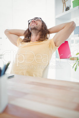 Happy hipster resting at desk in office