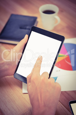 Man using digital tablet while documents and coffee on desk