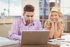 Business woman wearing hat sitting by male colleague