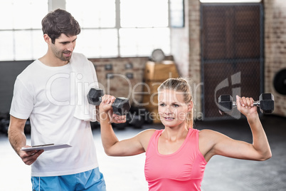 Fit woman lifting dumbbells with trainer