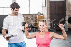 Fit woman lifting dumbbells with trainer