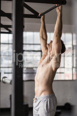 Muscular man lifting himself up and down