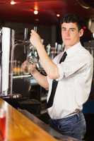 Portrait of barkeeper holding glass at beer dispenser