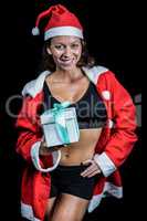Portrait of female athlete holding Christmas gift with hand on h