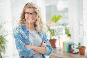 Portrait of smiling businesswoman wearing eyeglasses with arms c