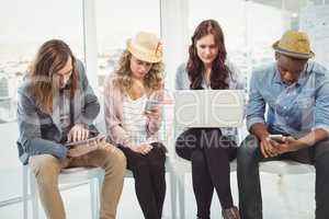 Business people using technology while sitting on chair