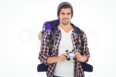 Happy hipster wearing backpack holding binoculars