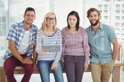 Portrait of smiling business people with digital tablet at desk