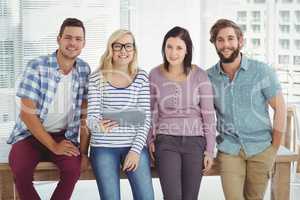 Portrait of smiling business people with digital tablet at desk